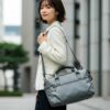 軽いブランド通勤バッグを持って街を歩く30代の日本人女性。洗練された通勤スタイル