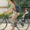後部に子ども用シートが付いた自転車に乗る日本人ワーママ。大容量リュックを背負い、通勤中の朝のシーン。